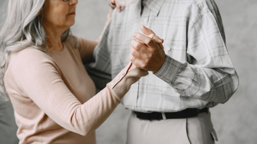 Ældre par holder hinanden i hånden og danser.