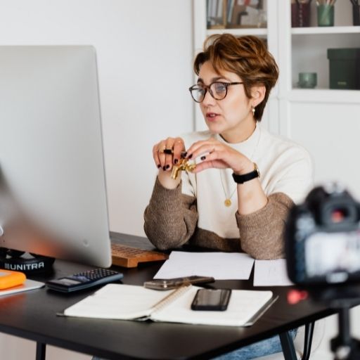 Ældre kvinde med briller sidder foran computerskærm.