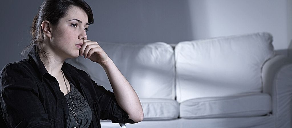 Kvinde med trist udseende med hånden på ansigtet.